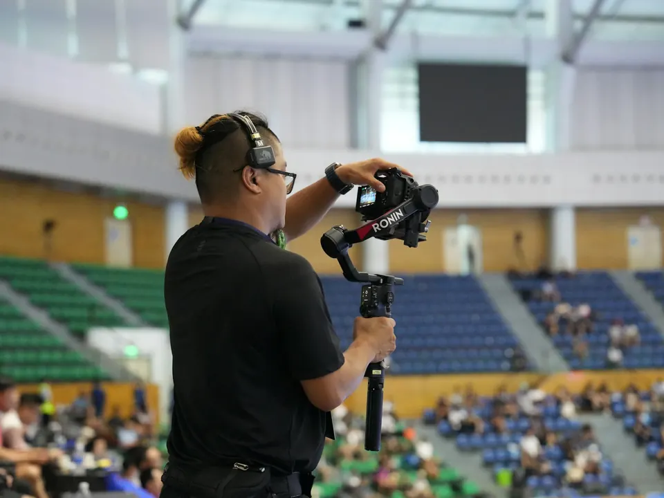Videógrafo con estabilizador grabando en una arena deportiva