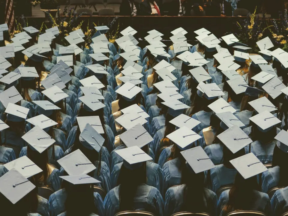 Birretes de graduación sobre las butacas de un auditorio