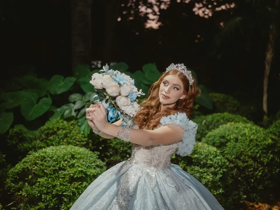 Quinceañera con vestido de gala y ramo de flores